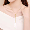 Gold-tone lariat necklace worn with a white top
